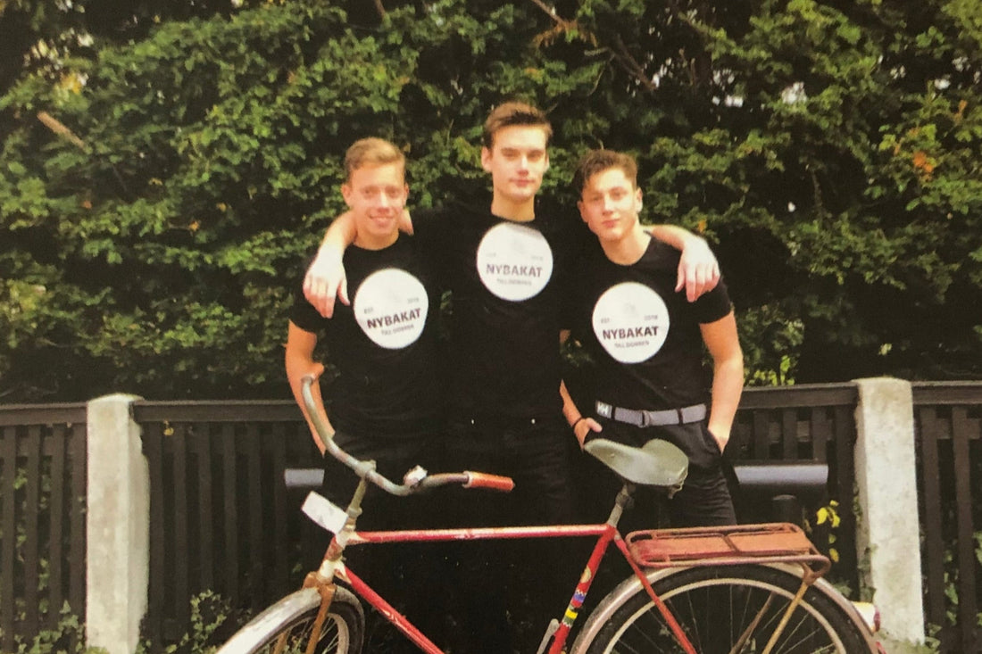 Tre ungdomar med Nybakat-tröjor och den röda leveranscykeln